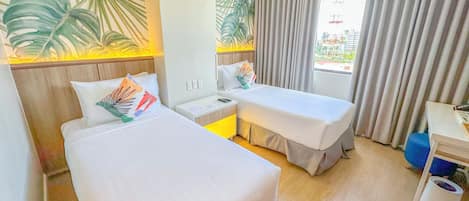 A hotel room with two beds, a nightstand, a desk, a chair, and a window with curtains.