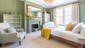 A bedroom with a bed, a chair, a fireplace, and a large window. - Luxuriously Designed 3 Bedroom Apartment in Clapham (London)