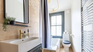A modern bathroom with a large sink, a bathtub, and a toilet. - Luxuriously Designed 3 Bedroom Apartment in Clapham (London)