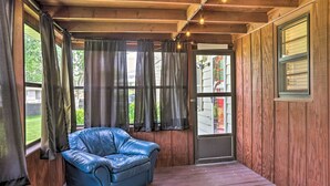 Eine Holzhütte mit blauem Ledersessel, Holzwänden und einer Tür mit Blick auf ein Haus.