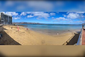 A beach with a building in the background. - Canteras Beach Apartment (Palmas De Gran Canaria, Las)
