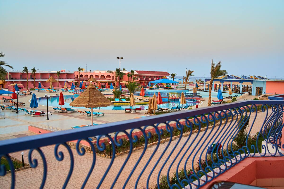 A resort with a swimming pool, sun loungers, and umbrellas.