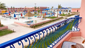 A resort pool area with lounge chairs and umbrellas, a children's play area, and a view of the sea. - MG Alexander The Great (Marsa Alam)