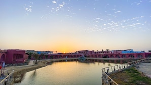 A riverside view with a bridge and buildings during sunset. - MG Alexander The Great (Marsa Alam)