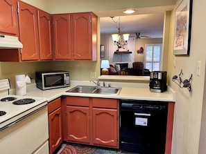 A compact kitchen with a microwave, stove, sink, and dishwasher.