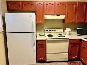 A kitchen with a white refrigerator, stove, and microwave.
