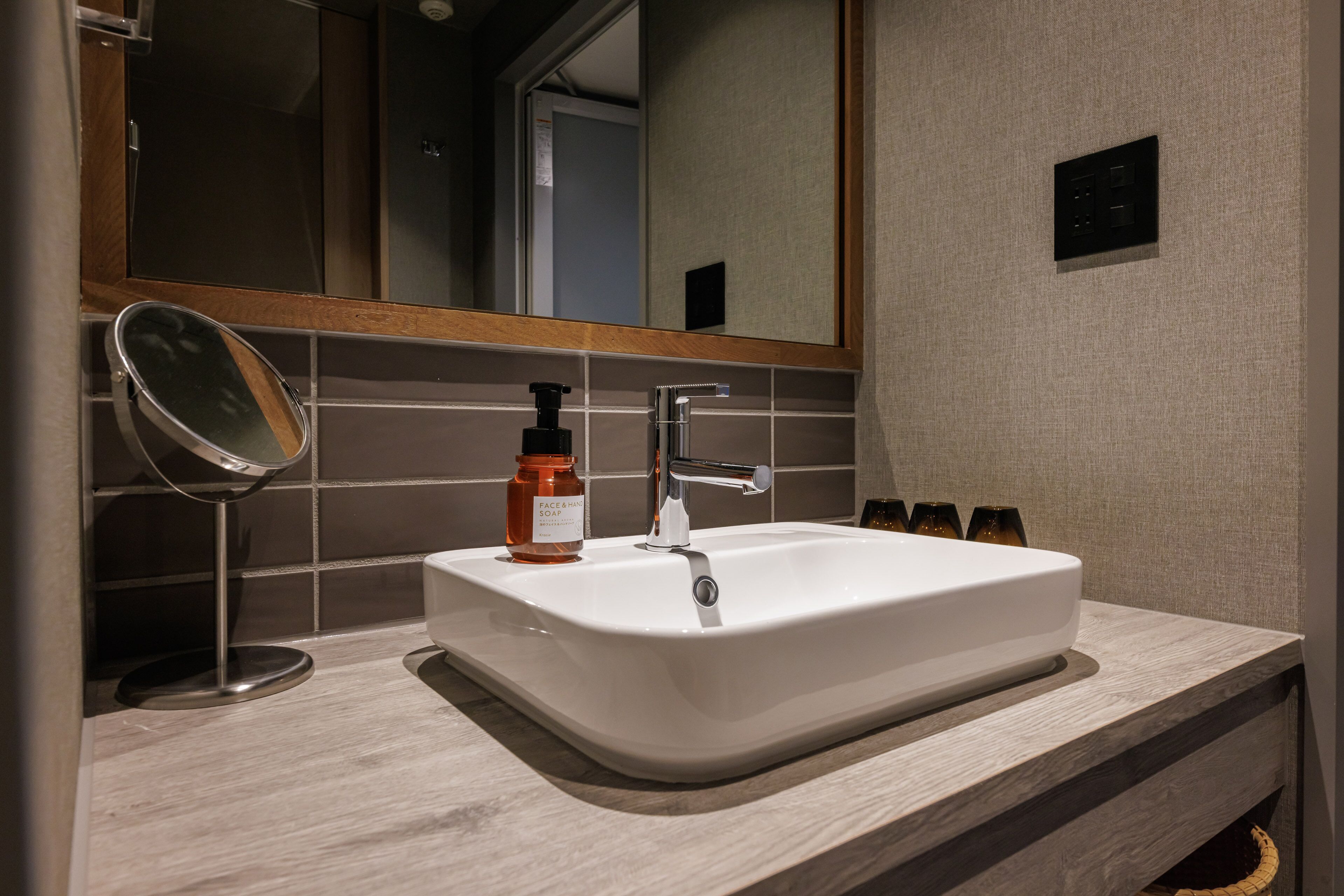 A bathroom with a white sink, a mirror, and a bottle of soap.