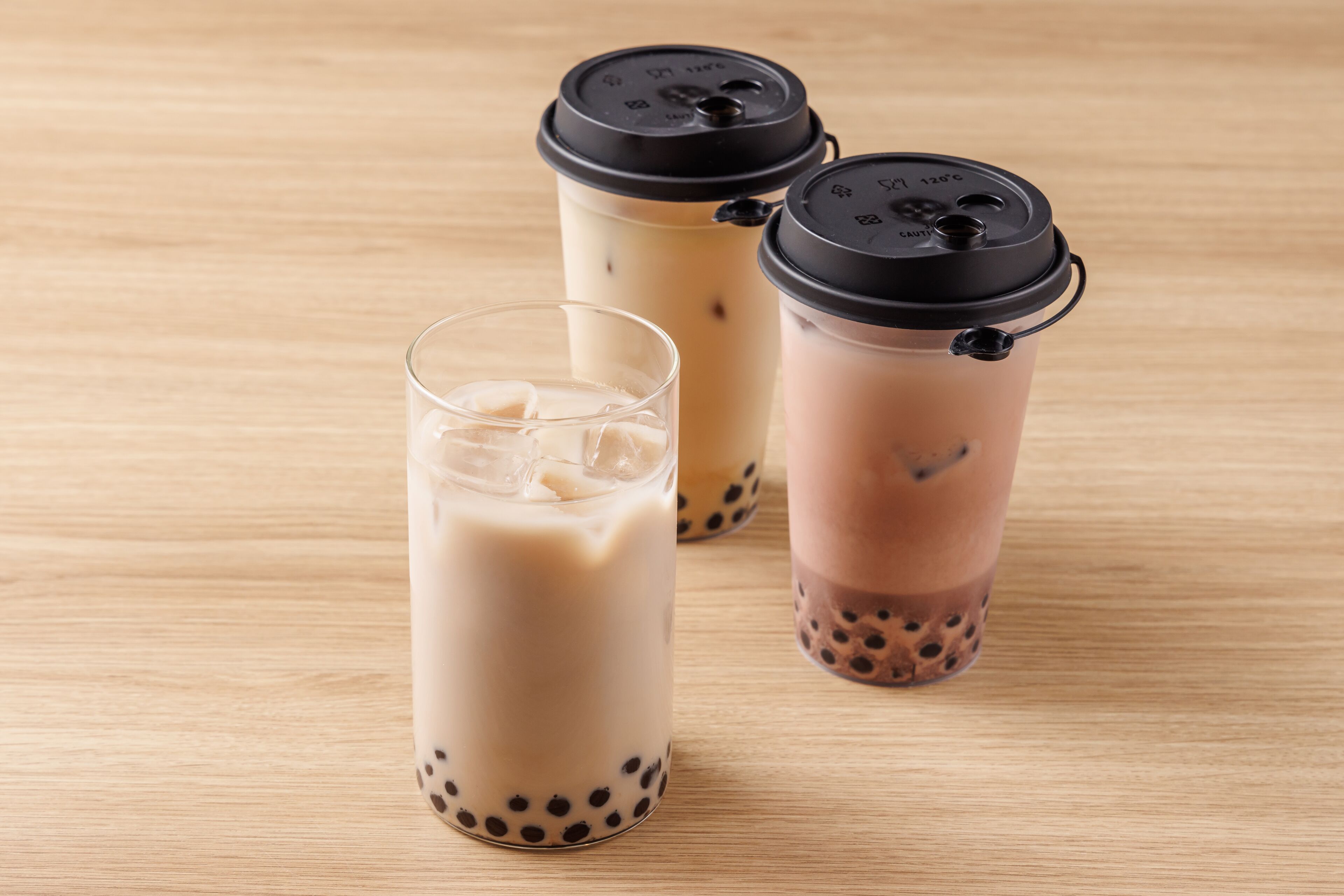 Drie bubble tea drankjes op een houten oppervlak.