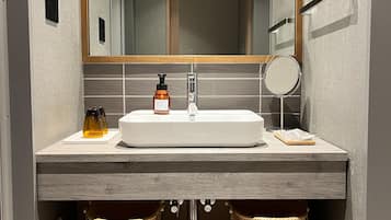A bathroom with a large mirror, a sink, two wicker baskets, and a bottle of soap.