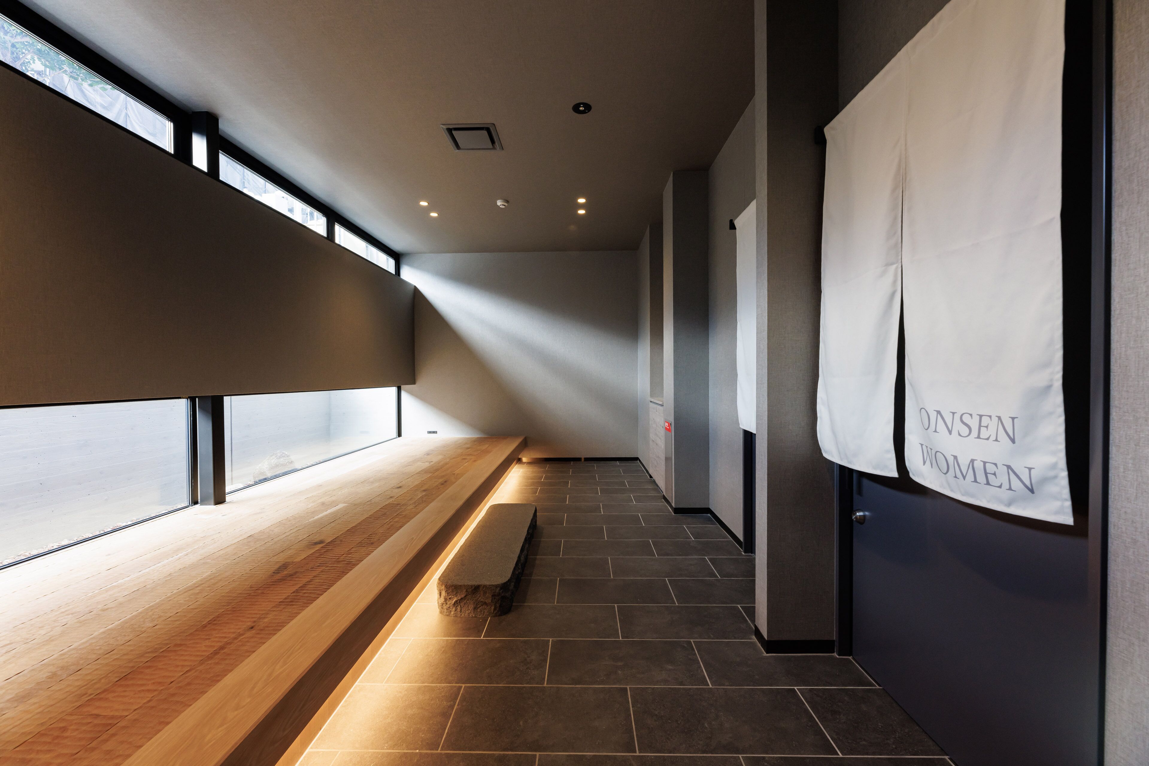 A corridor with a bench, a wall-mounted sign, and a window.