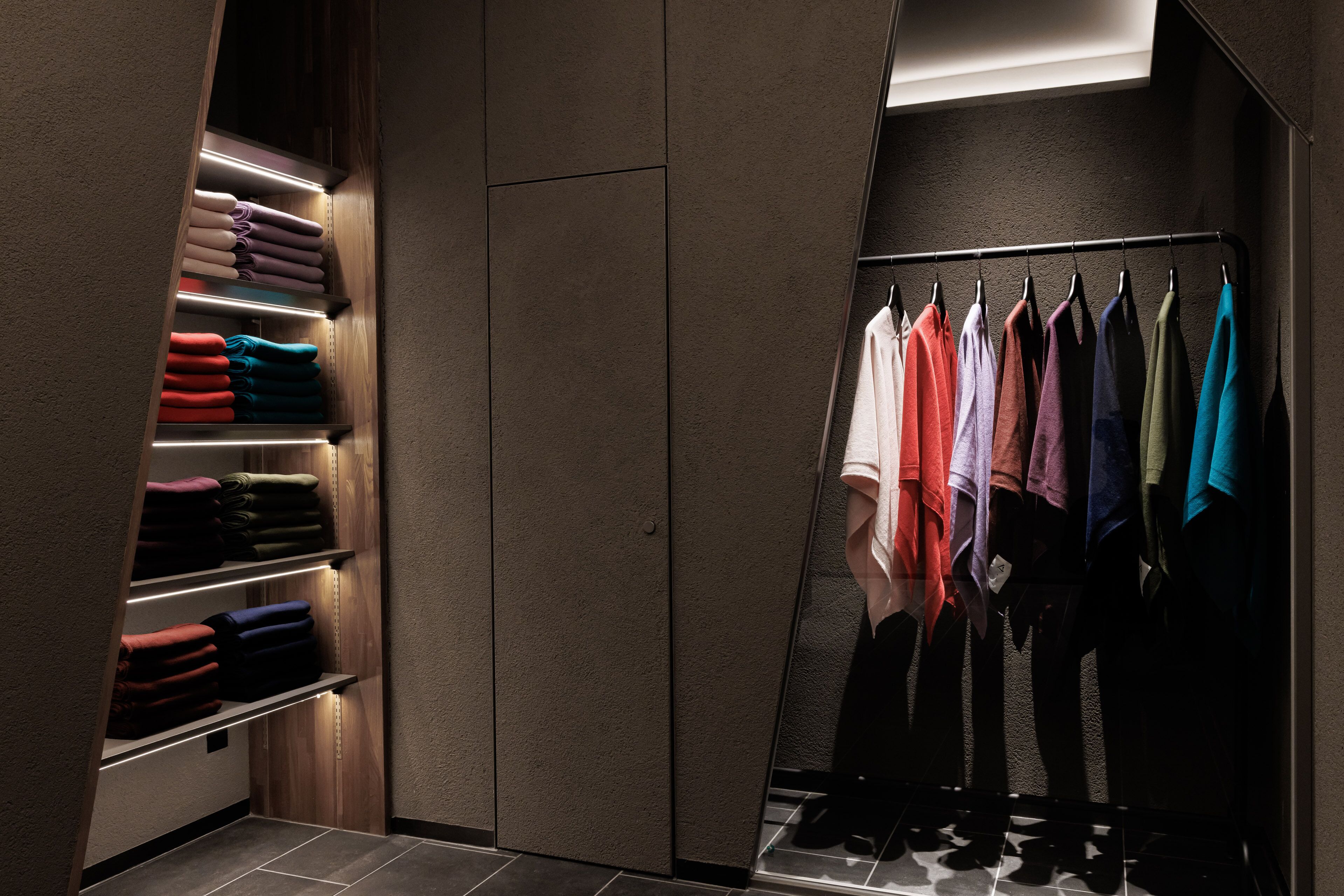 A modern closet with shelves for folded clothes and a rack for hanging items.