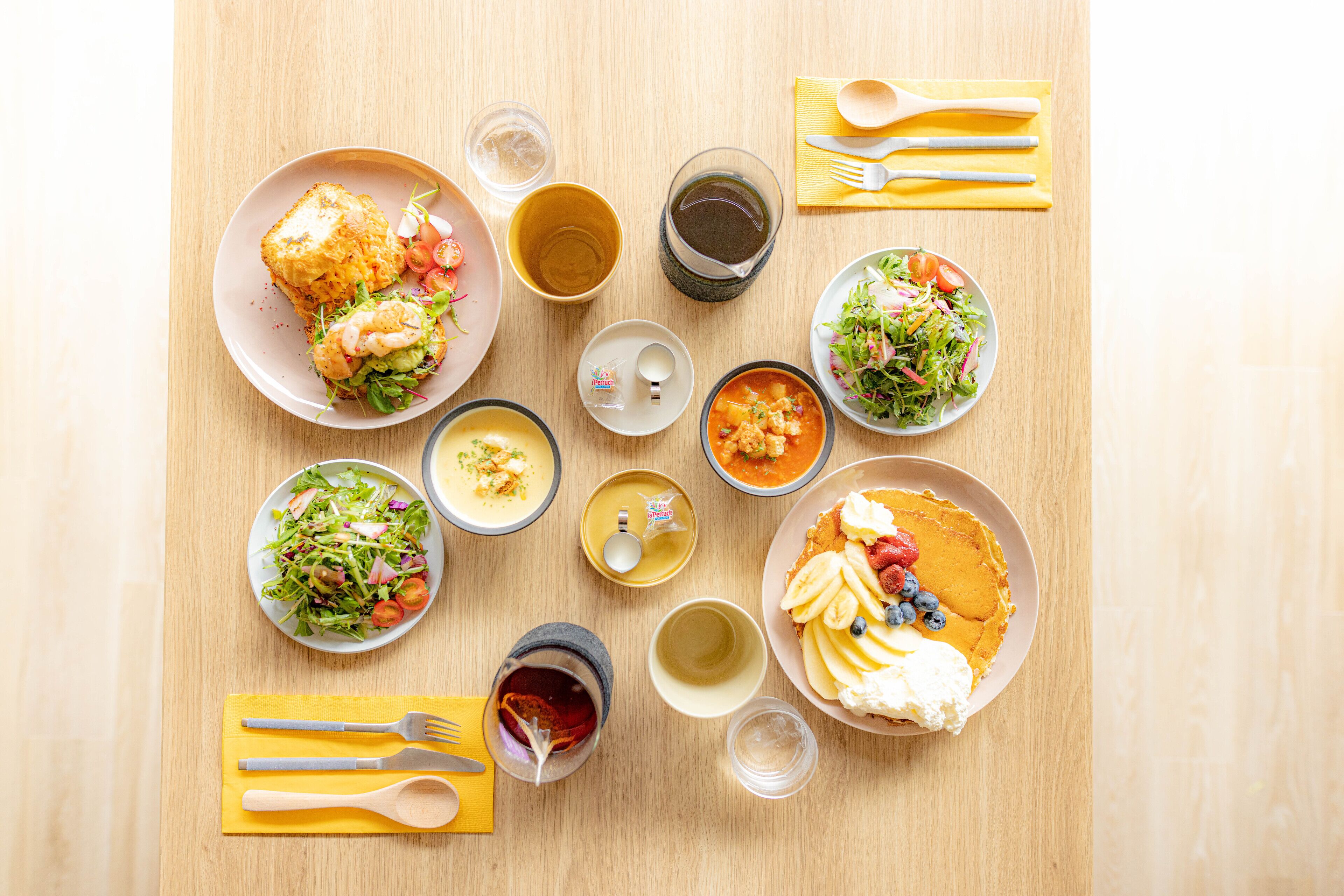 A table with various dishes, including a salad, soup, and a dessert with fruit.