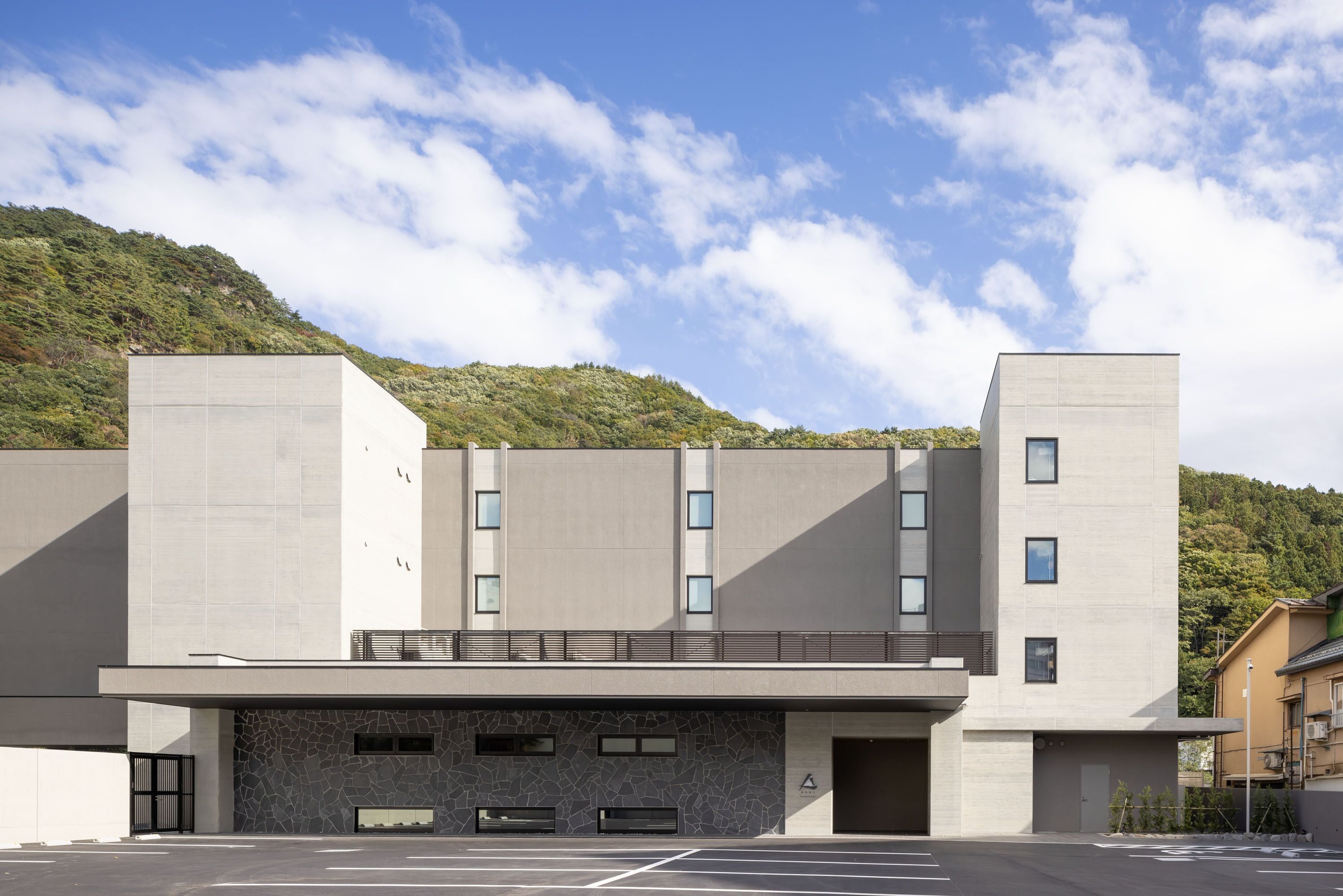 Un bâtiment moderne doté d’un toit plat, de grandes fenêtres et d’une façade en pierre.