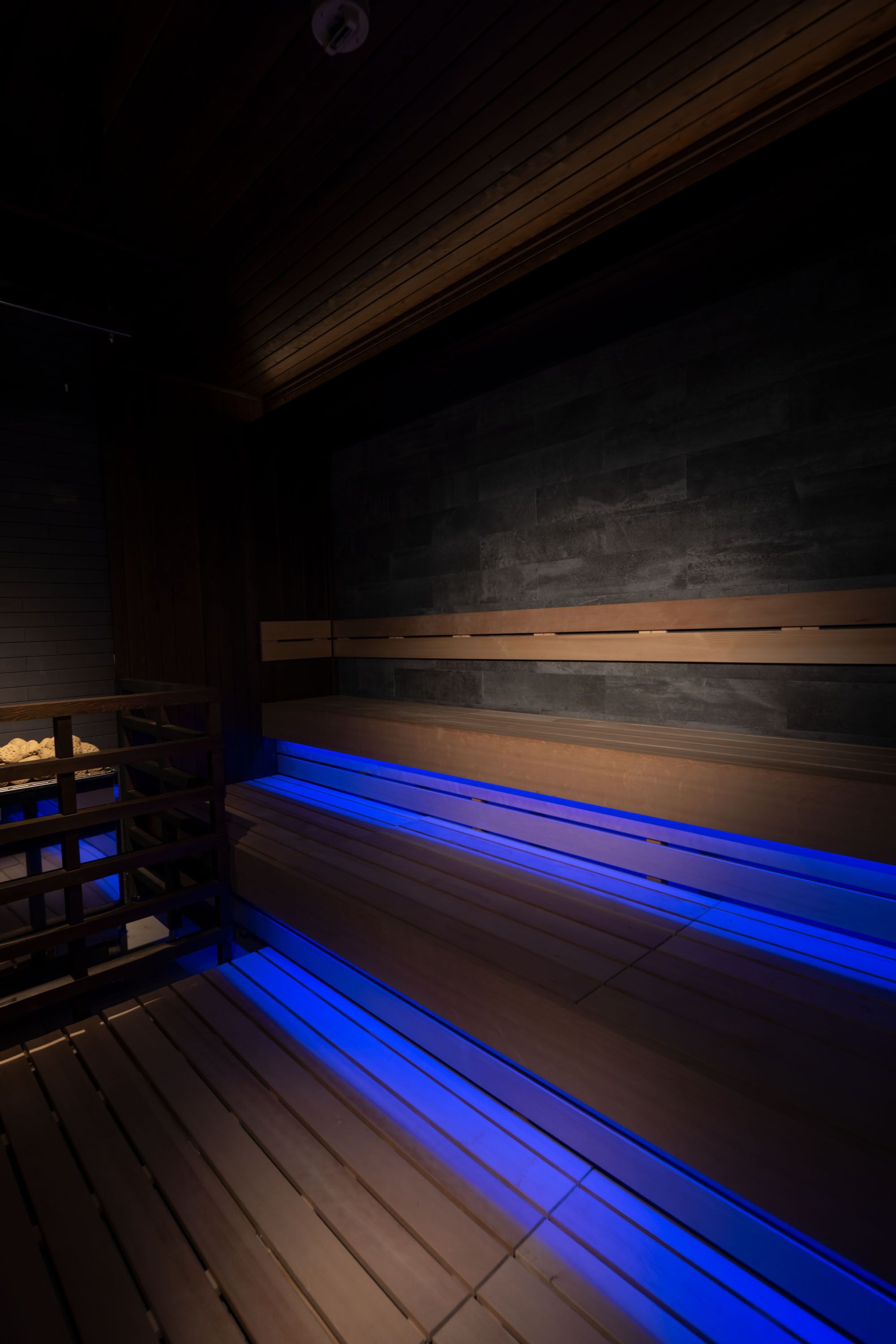 Un sauna avec des bancs en bois et un sol illuminé de lumière bleue.