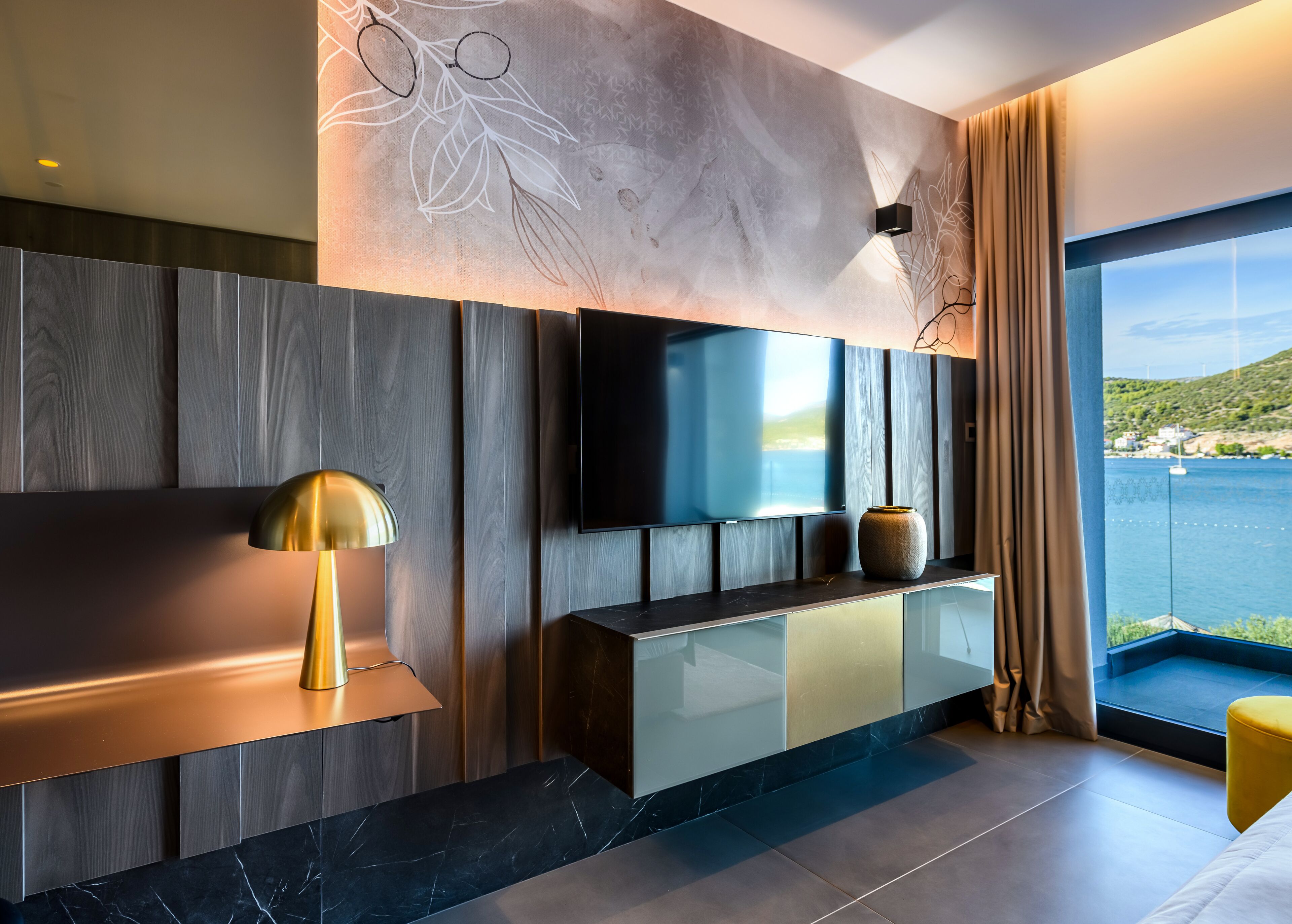 A modern living room with a large flat-screen TV, a gold lamp, and a vase on a console table.
