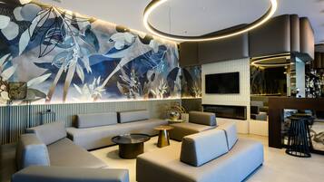 A modern lounge area with a large abstract mural, comfortable seating, and a bar area with a television.