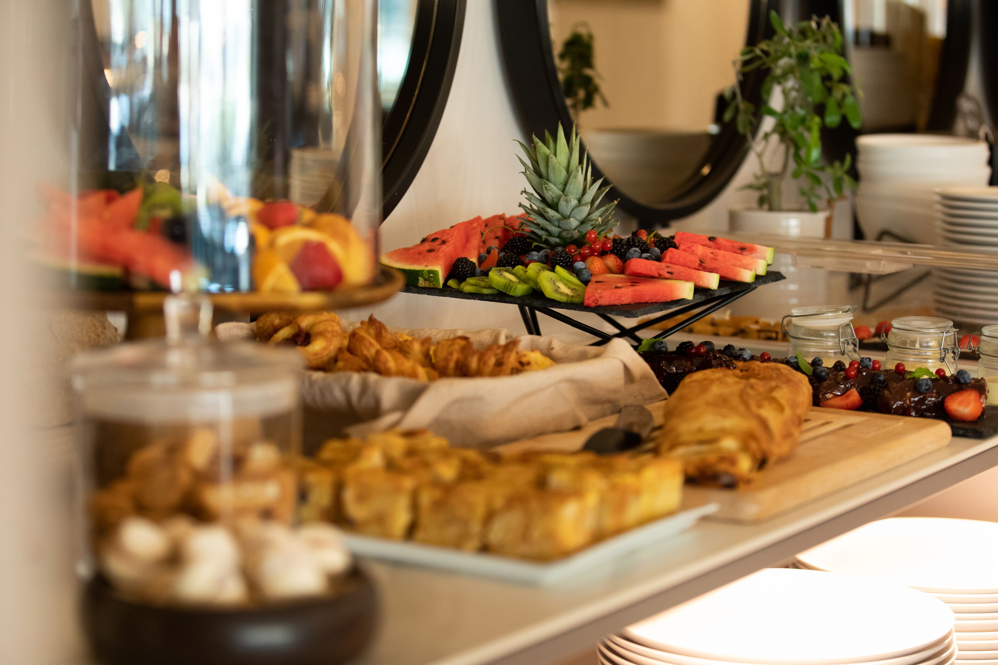 Een buffet met diverse soorten eten, waaronder fruit, gebak en een selectie kazen.