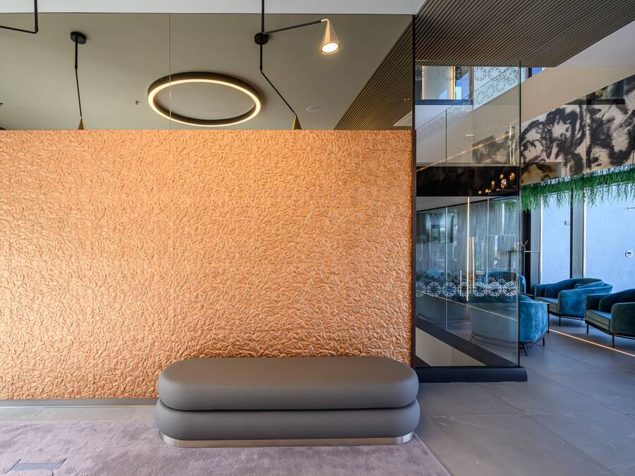 Un interior moderno con pared texturizada, iluminación empotrada y una zona de estar.