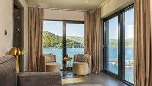 A modern room with a large window, two seating areas, and a small table with fruit. - Marinus Beach Hotel (Marina)