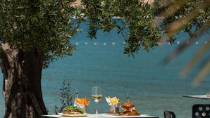 A table with a meal, a glass of wine, and a view of the sea. - Marinus Beach Hotel (Marina)