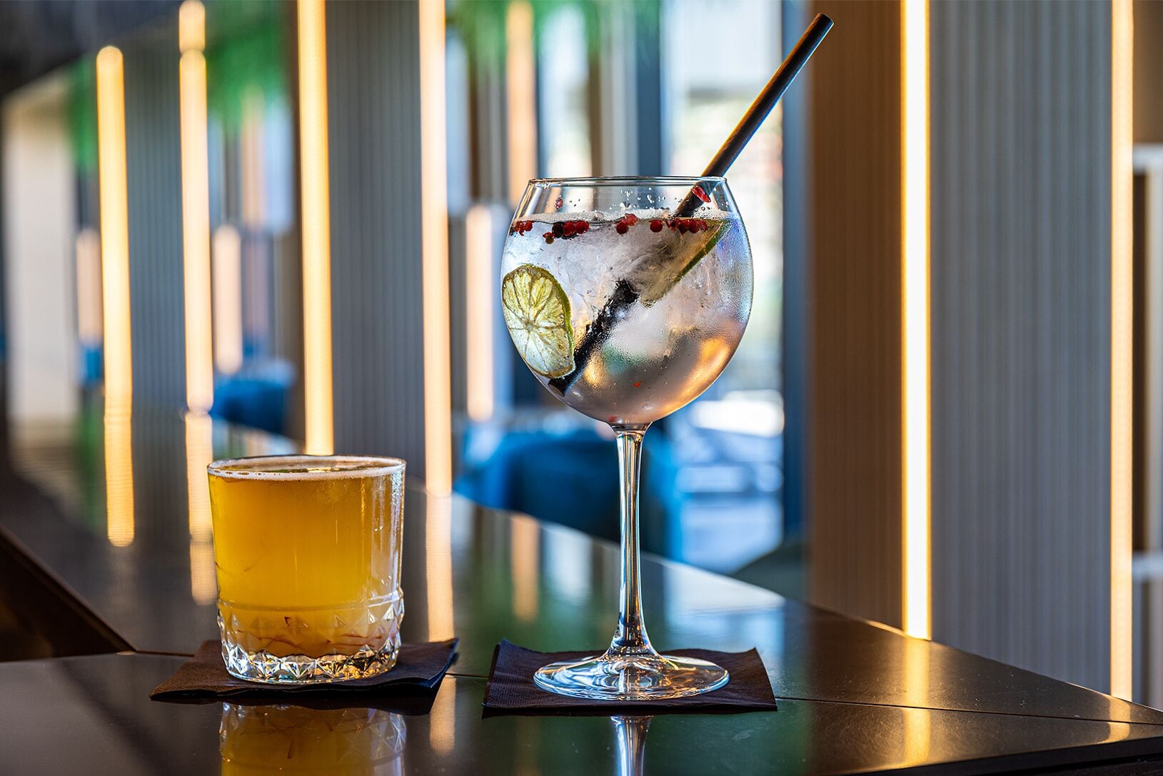 Deux verres de boissons sur le comptoir d’un bar au décor intérieur moderne.