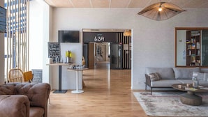 A modern interior with a sofa, a coffee table, and a bookshelf. - Hôtel l'escale marine (Crozon)