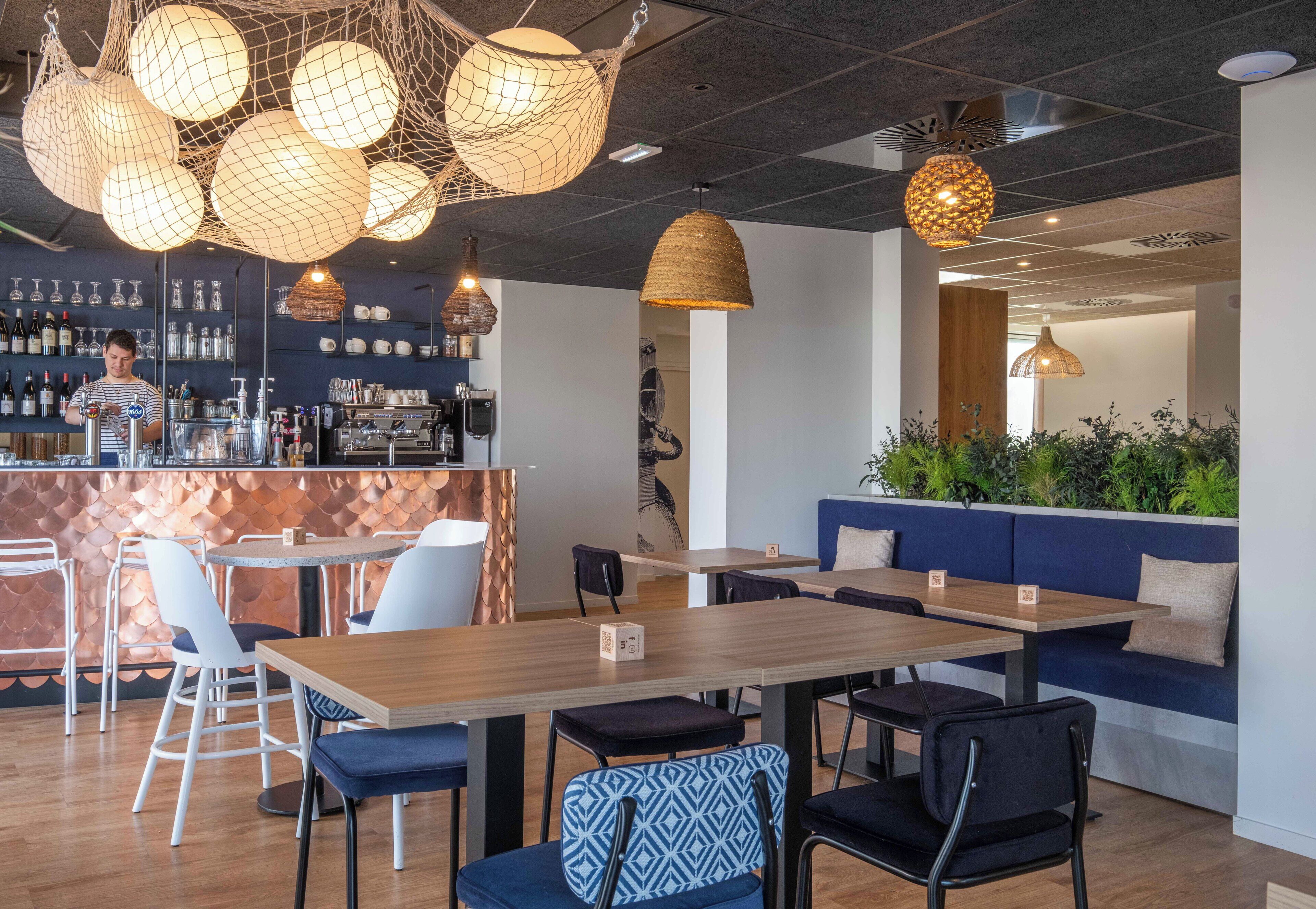 A modern restaurant interior with a bar area, seating arrangements, and decorative lighting.