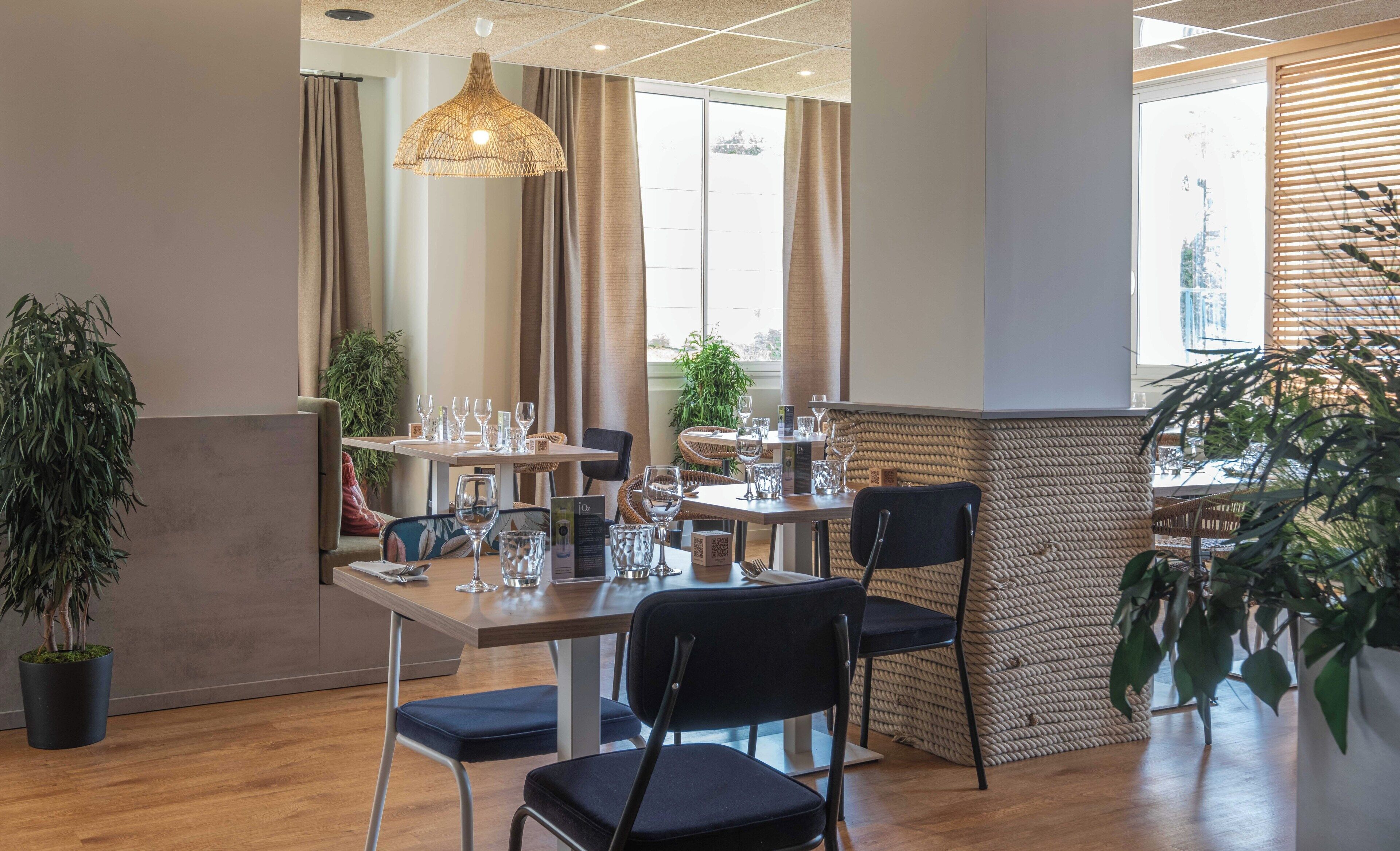 Un comedor moderno con una mesa de madera, sillas negras y una lámpara colgante.