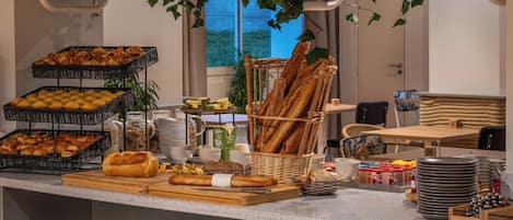 A breakfast buffet with various pastries, bread, and beverages.