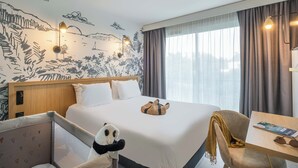 A hotel room with a large bed, a bedside table with a magazine, a panda plush toy, and a mural on the wall. - Hôtel l'escale marine (Crozon)