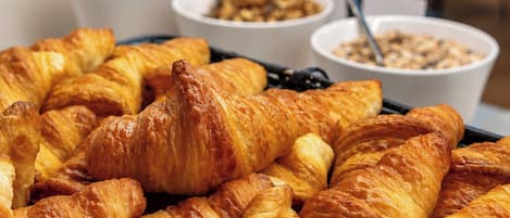 A buffet with croissants and bowls of food.