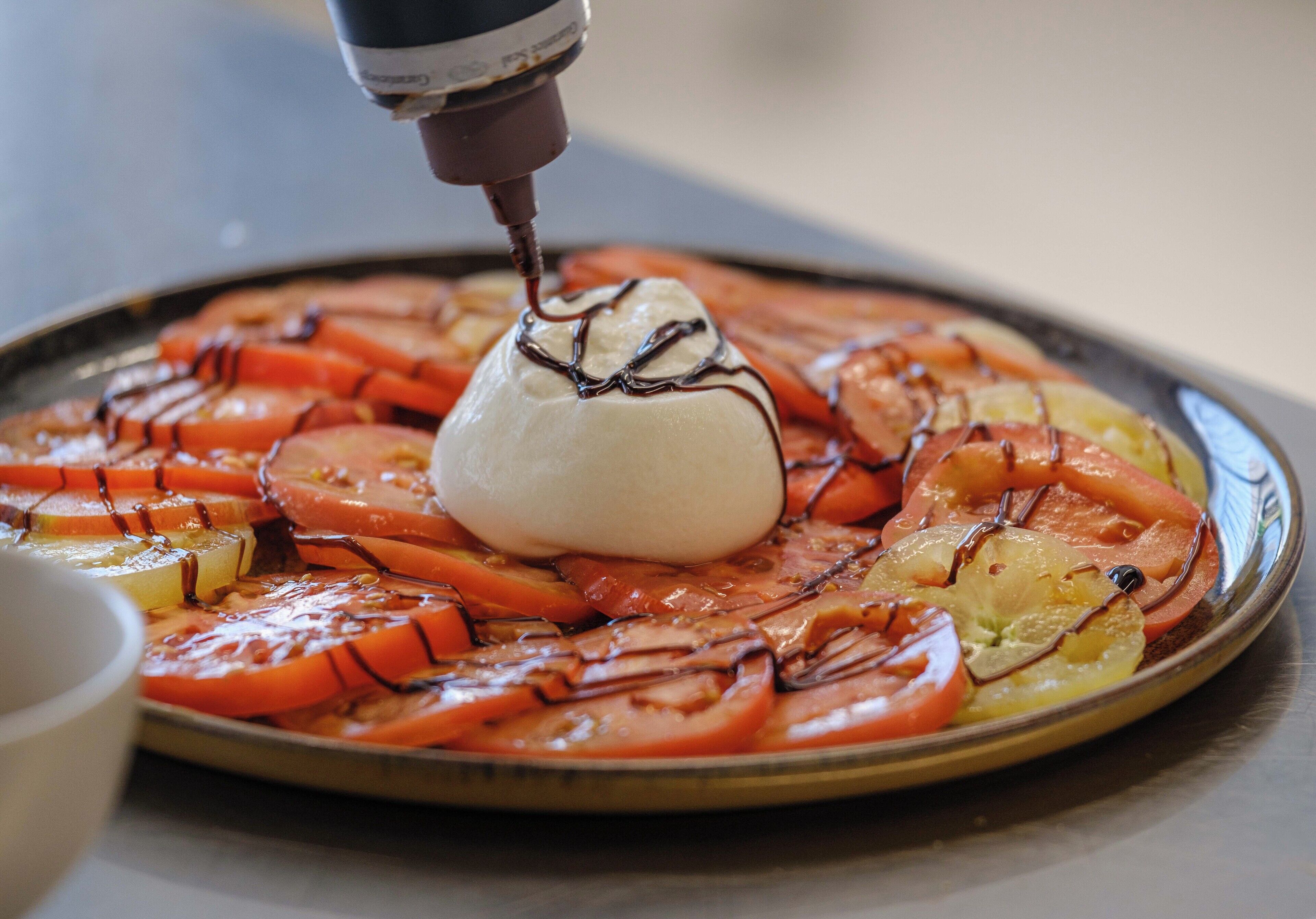 A plate of food with a grilled tomato and mozzarella on a plate.