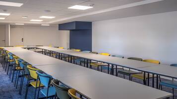 A conference room with a long table and multiple chairs, white walls, and a blue accent wall.