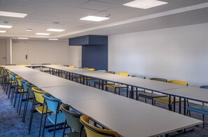 A conference room with a long table and multiple chairs, white walls, and a blue accent wall. - Hôtel l'escale marine (Crozon)