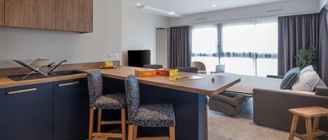 Una cocina moderna con una isla central, taburetes de bar, zona de comedor y vistas a la ciudad.