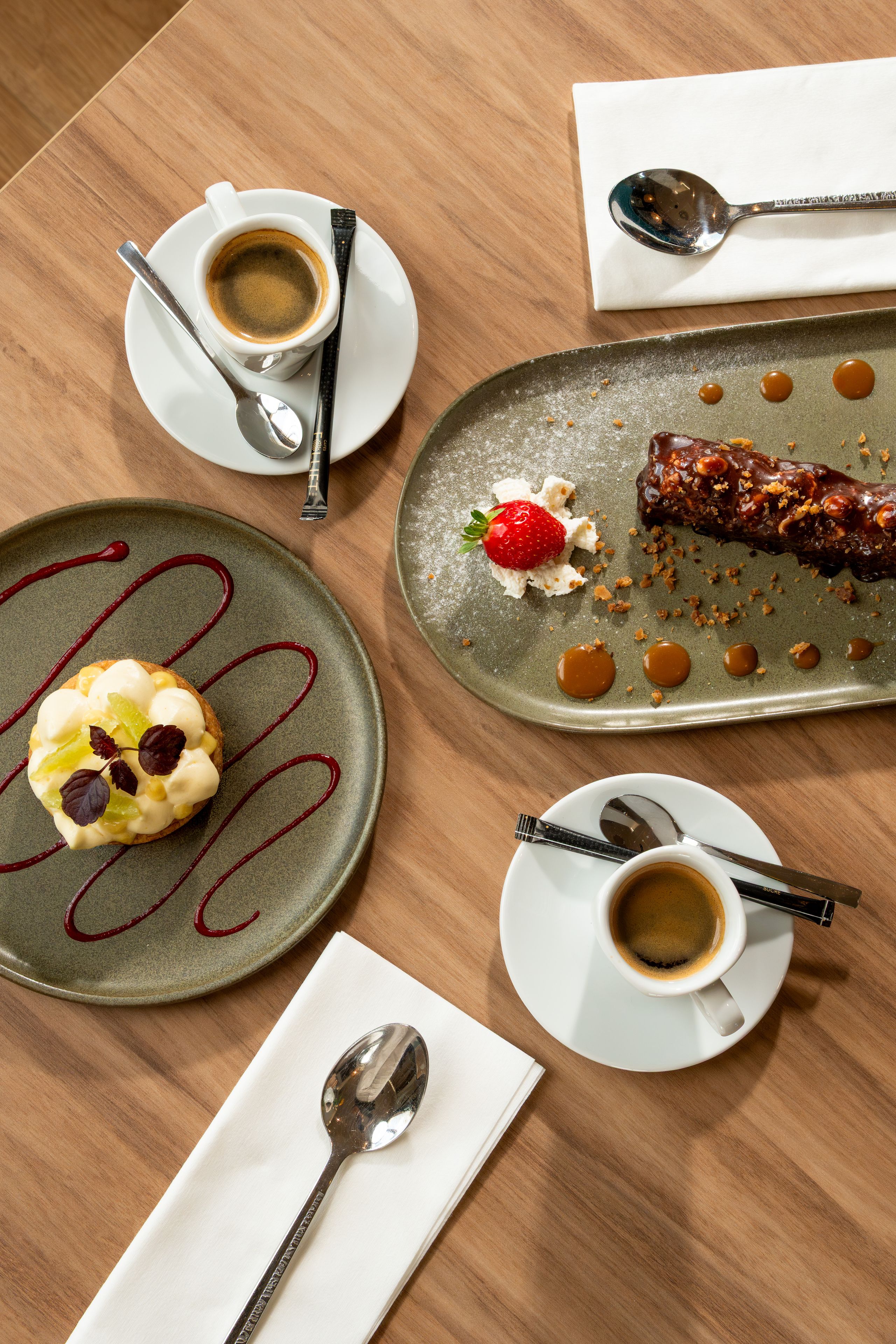 A table with a dessert plate, two cups of coffee, and a spoon.
