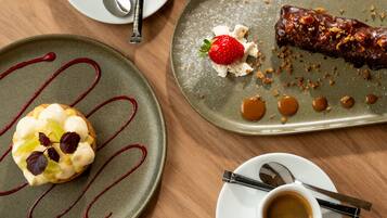 A table with a dessert plate, two cups of coffee, and a spoon.