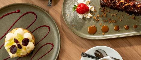 Une table avec une assiette à dessert, deux tasses de café et une cuillère.