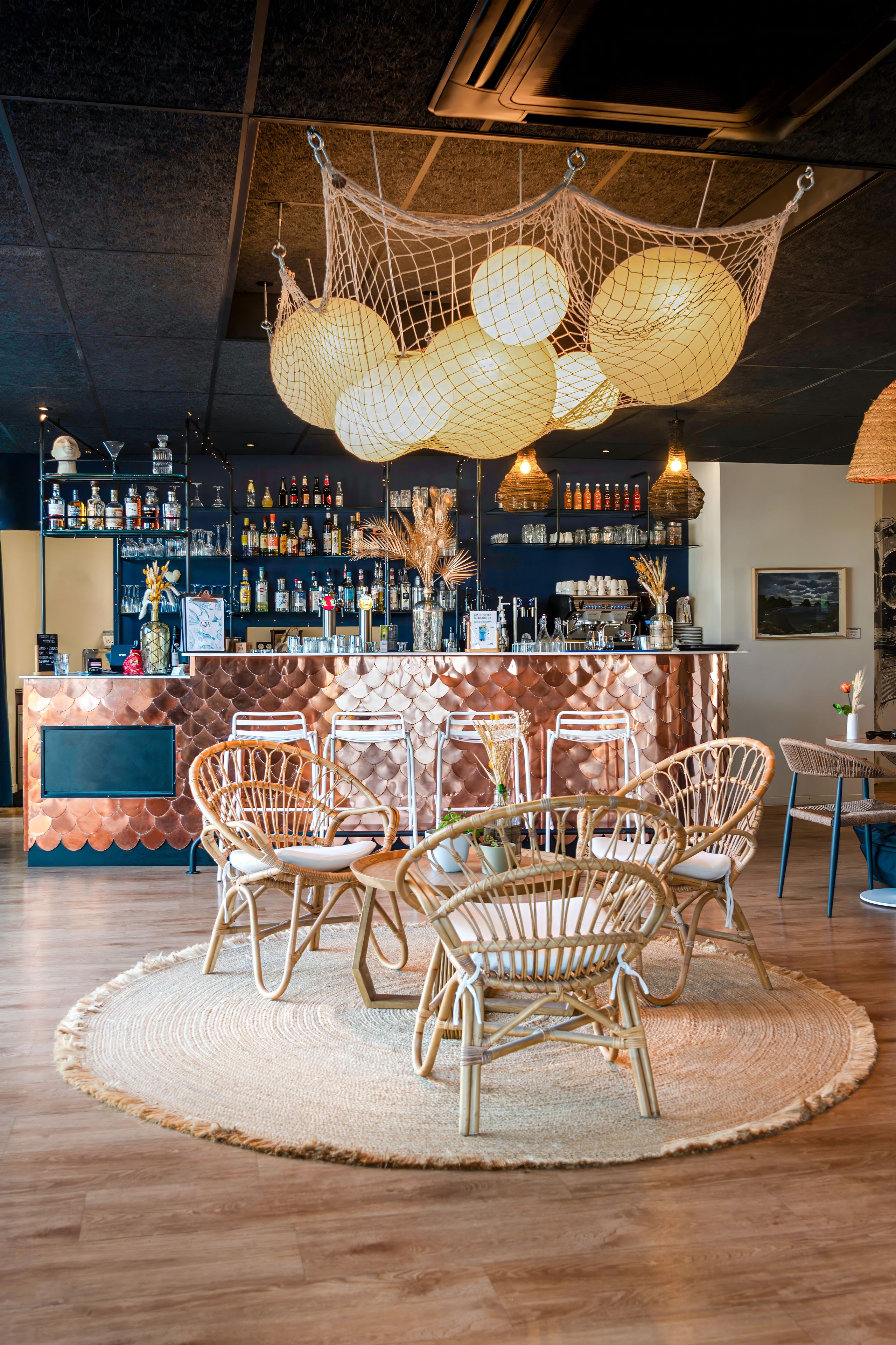 A bar area with wicker chairs, a round table, and a hanging light fixture.