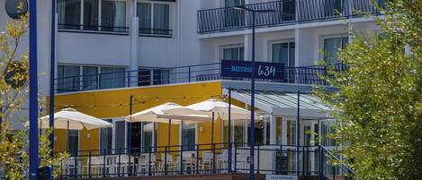 A bistro with outdoor seating, a yellow awning, and a sign indicating a seminar room.