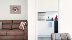 A modern living room with a brown sofa, a striped pillow, and a framed abstract artwork on the wall. - Central two-room apartment with balcony (LOCARNO CITY 2) (Locarno)