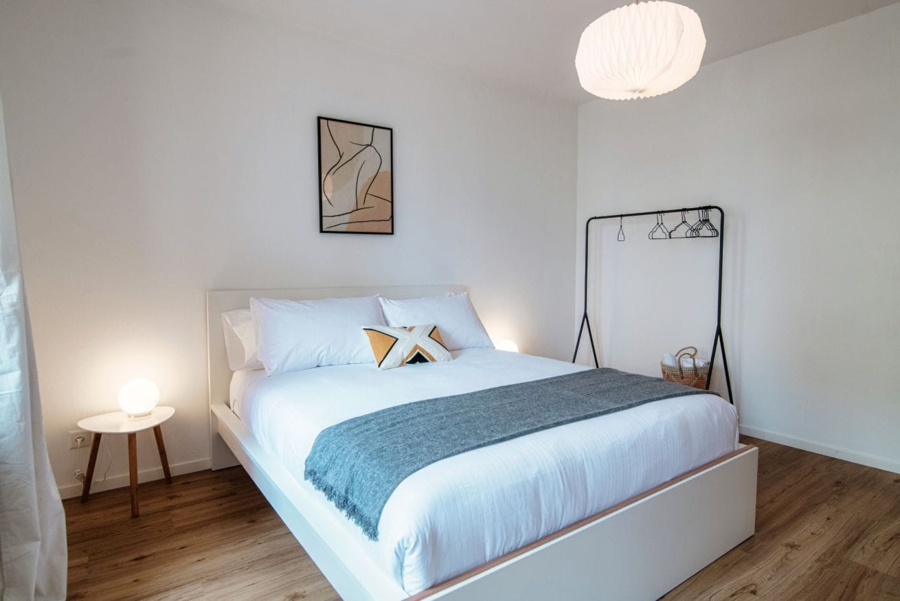 Une chambre à coucher moderne avec un lit, une table de chevet et une étagère fixée au mur.