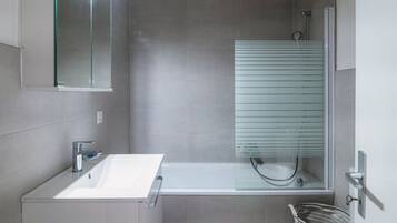 A modern bathroom with a white sink, a glass-enclosed shower, and a mirror above the sink.