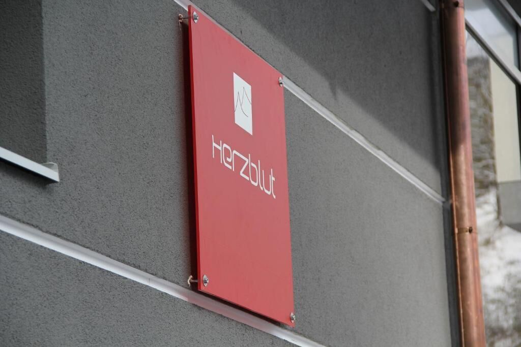 A red sign with the text "Hertzblut" on a grey wall.