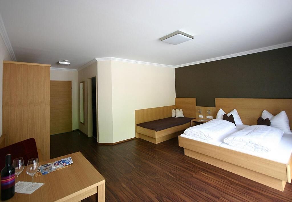 A hotel room with a bed, bedside table, and a small seating area.