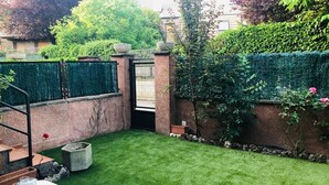 Un jardin bien entretenu, avec une pelouse soigneusement taillée, un mur en briques et un portail en métal.