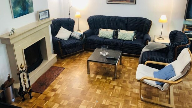 Un salon avec une cheminée, un ensemble de canapés, une table basse et deux lampadaires.