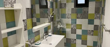 A bathroom with a tiled shower wall, a white sink, and a mirror.