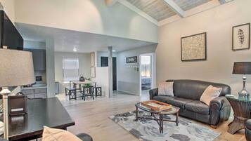A spacious living area with a dark leather sofa, a coffee table, and a dining table with chairs.