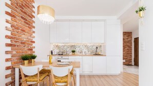 Une cuisine moderne avec des armoires blanches, un îlot central en bois et un mur d’accent en briques.